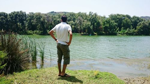 Rear view of man standing on riverbank