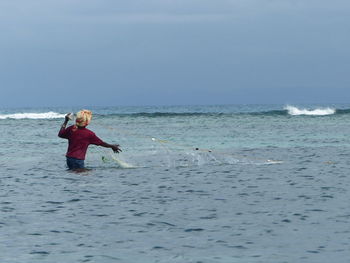 Full length of man fishing on sea against sky