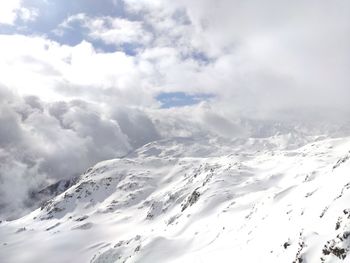 Snowcapped mountains against cloudy sky