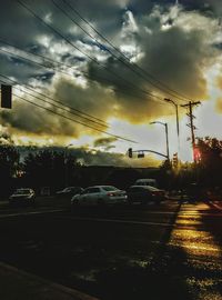 Cars on road against cloudy sky at sunset