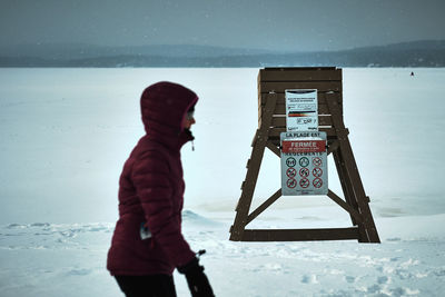 Side view of person wearing warm clothing standing on snow covered landscape