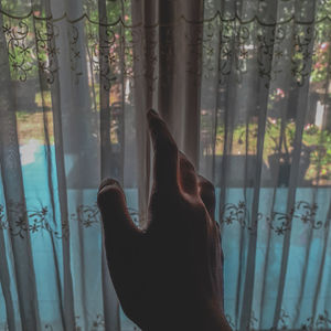 Cropped hand of woman touching curtain