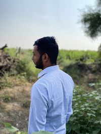 Side view of young man looking away on field