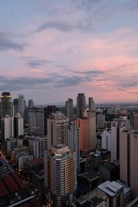 Modern buildings in city against sky during sunset