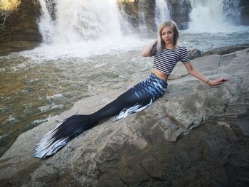 Mermaid sun bathing on the rocks by the waterfalls 