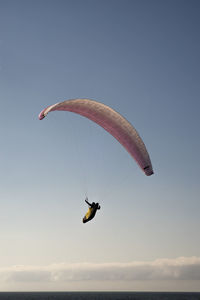 Low angle view of man paragliding against sky