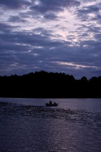 Silhouette boat in lake against sky