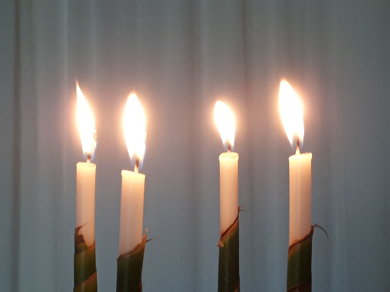 CLOSE-UP OF CANDLES BURNING AGAINST WALL