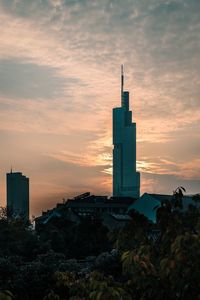 Tower amidst buildings against sky during sunset