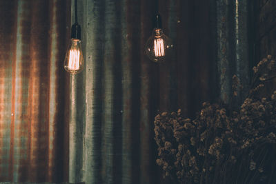 Illuminated light bulbs hanging against wall