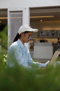 Side view of teenage girl reading menu while sitting in cafe