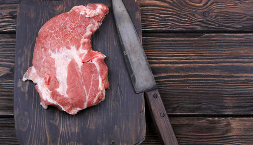 Chopping cutting board with meat and a knife for slicing on the old wooden background with space 