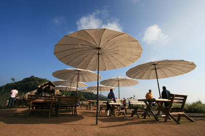 People under umbrella at restaurant against sky