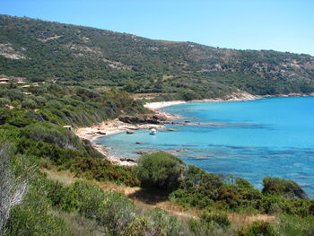 Scenic view of sea and mountains against clear blue sky