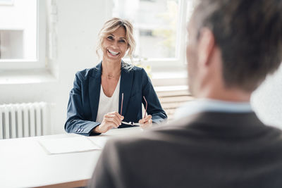 Happy businesswoman talking with man at office