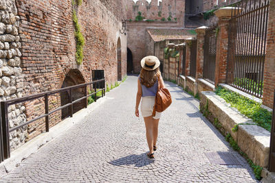 Beautiful tourist woman walking in the medieval city of verona on castelvecchio bridge, italy
