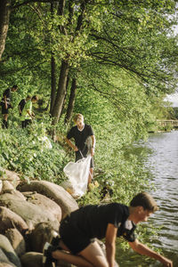 Teenage boys picking garbage from lakeshore