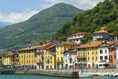 Houses by river amidst buildings against sky