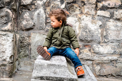 Full length of a boy sitting against wall