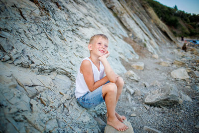 Portrait of smiling girl sitting on rock