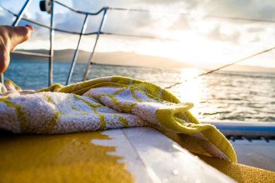 Cropped image of person relaxing on boat in sea during sunset