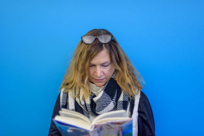 Woman reading book against blue background