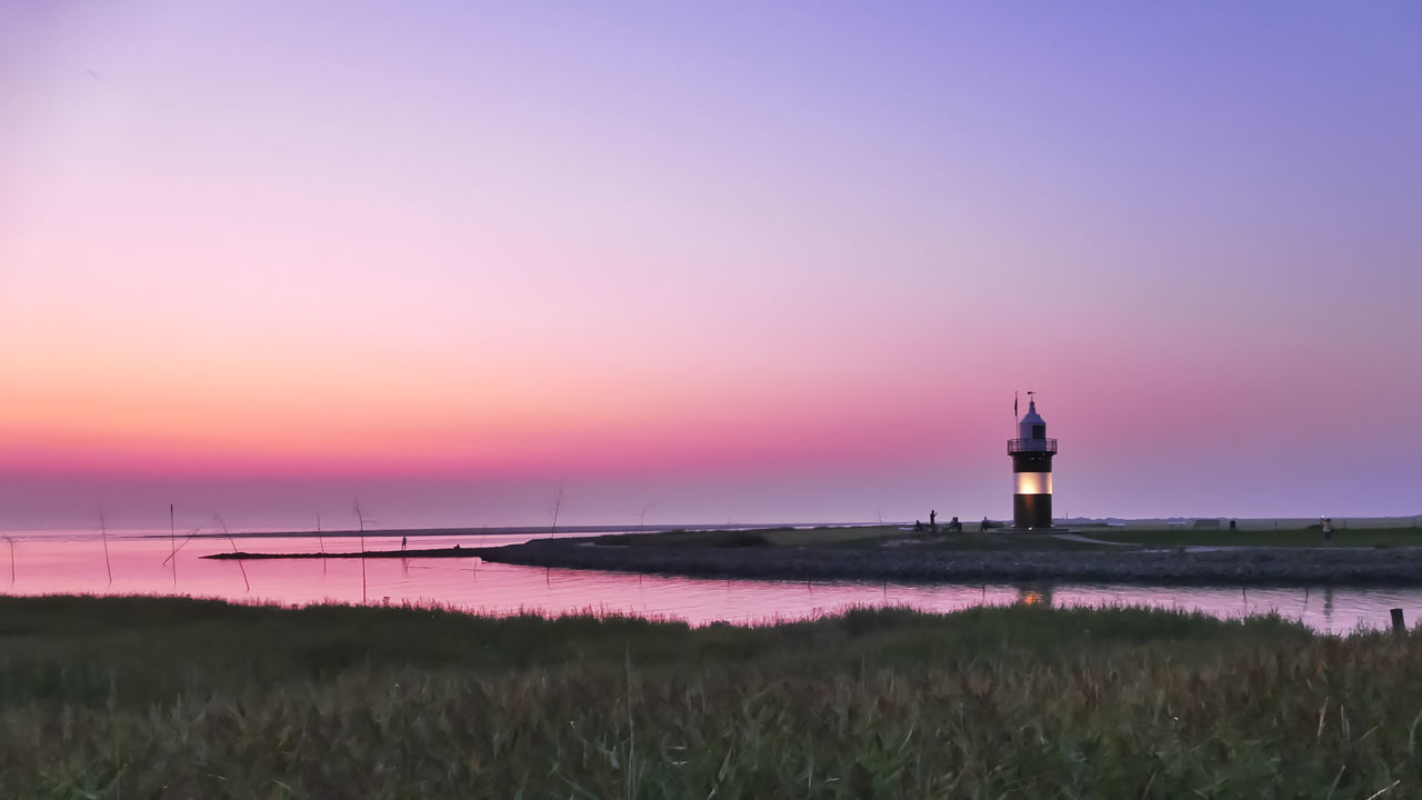 sky, sunset, lighthouse, tower, architecture, built structure, beauty in nature, building exterior, scenics - nature, guidance, nature, tranquility, water, grass, building, plant, no people, land, tranquil scene, purple