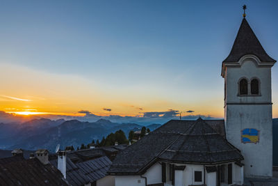 Houses and buildings against sky during sunset