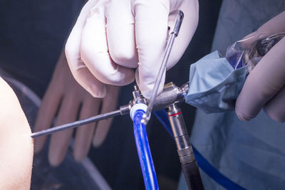 Cropped hands of doctor performing operation on patient knee in hospital