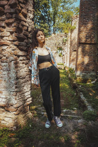 Portrait of young woman standing against wall