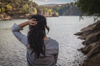 Rear view of woman standing by lake