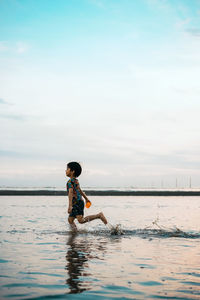 Side view of boy in sea against sky