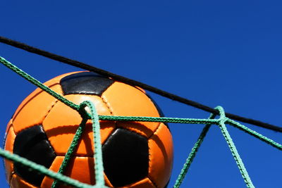 Low angle view of soccer ball on goal post against clear blue sky