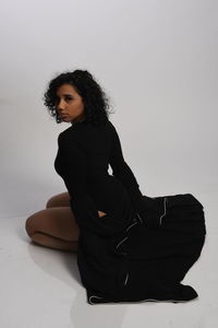 Young woman sitting on floor against white background