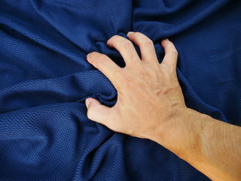 Cropped hand holding crumpled bed sheet