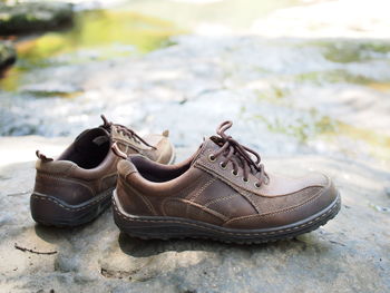 Close-up of shoes on rock by river