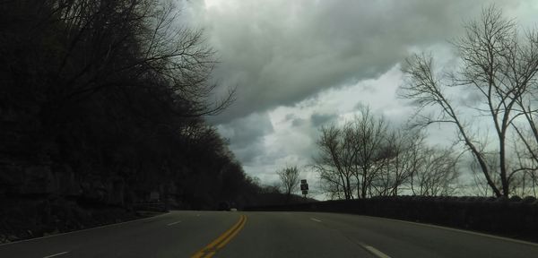 Empty road against cloudy sky