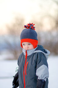 Boy wearing warm clothing looking away while standing outdoors