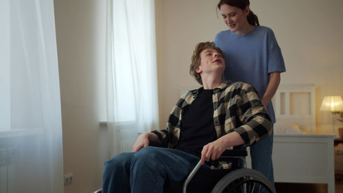 Nurse carrying man sitting on wheelchair at home