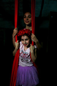 Woman with girl wearing floral crown against red curtain
