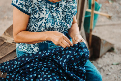 Midsection of woman sitting on wood