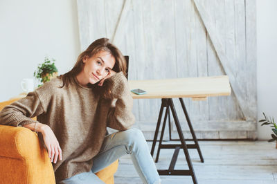 Young woman sitting on chair at home