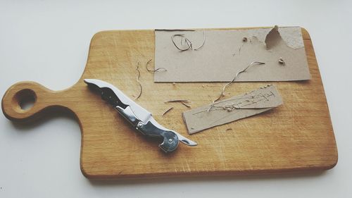 High angle view of knife with paper on cutting board at table