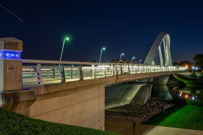 Illuminated bridge over canal in city at night