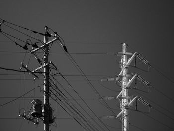 Low angle view of electricity pylon against clear sky