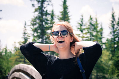 Smiling woman standing against trees