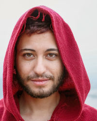 Close-up portrait of young man wearing red hooded shirt outdoors