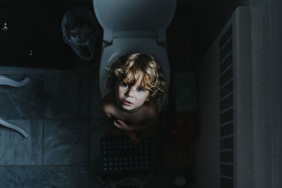 High angle portrait of shirtless girl in toilet
