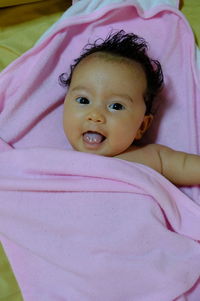 Portrait of cute baby girl lying on bed