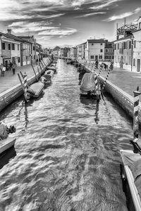 Boats in canal amidst buildings in city against sky